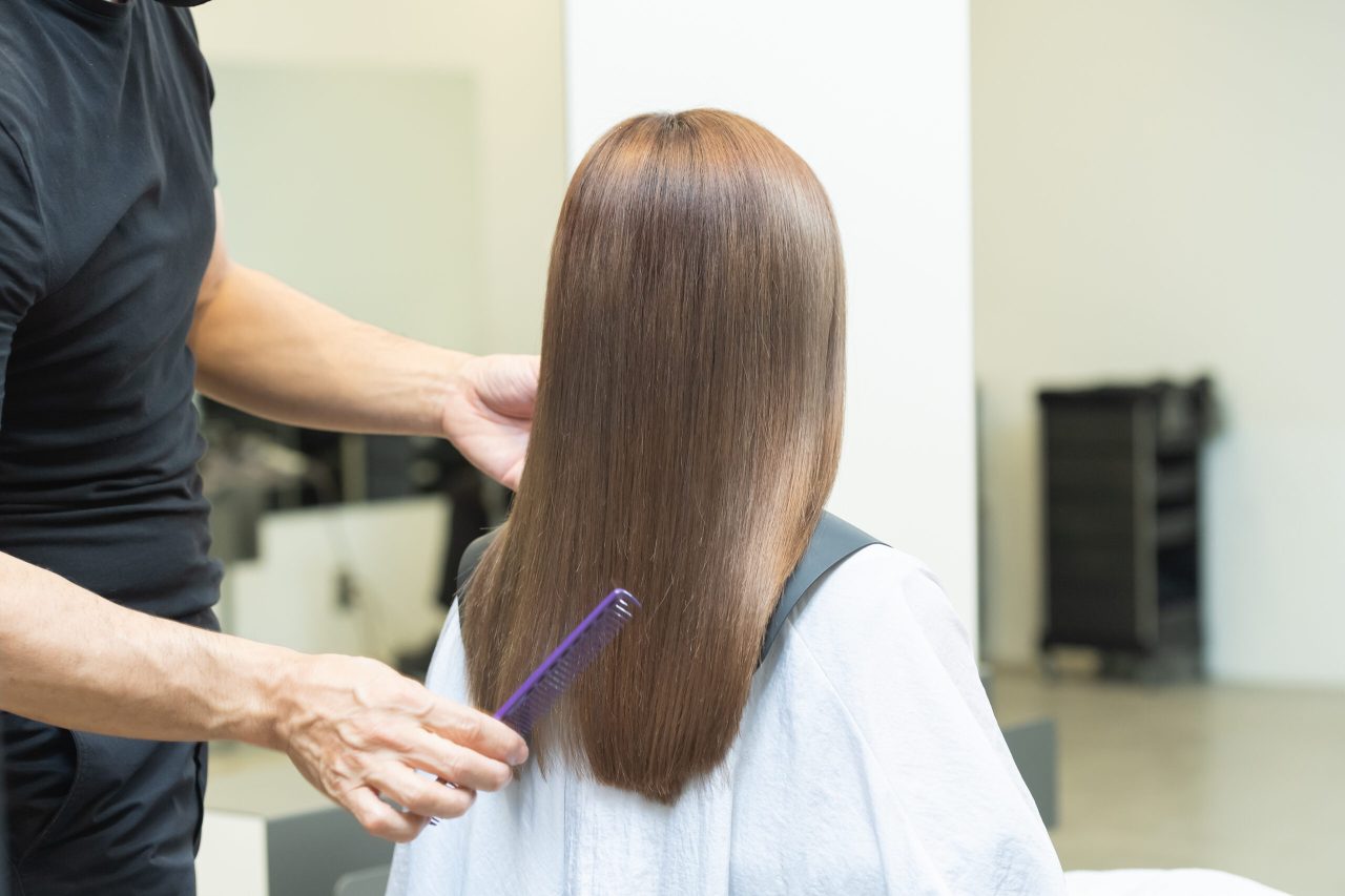 ヘアサロンで髪の毛をセットするスタイリスト