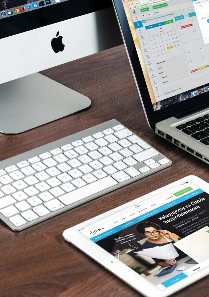 A sleek office desk setup featuring Apple devices: iMac, MacBook, and iPad.